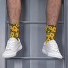 A pair of white sneakers worn with yellow sunflower print breathable crew socks against a gray background.
