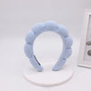 Light blue sponge terry cloth headband for hair styling displayed on a white stand.