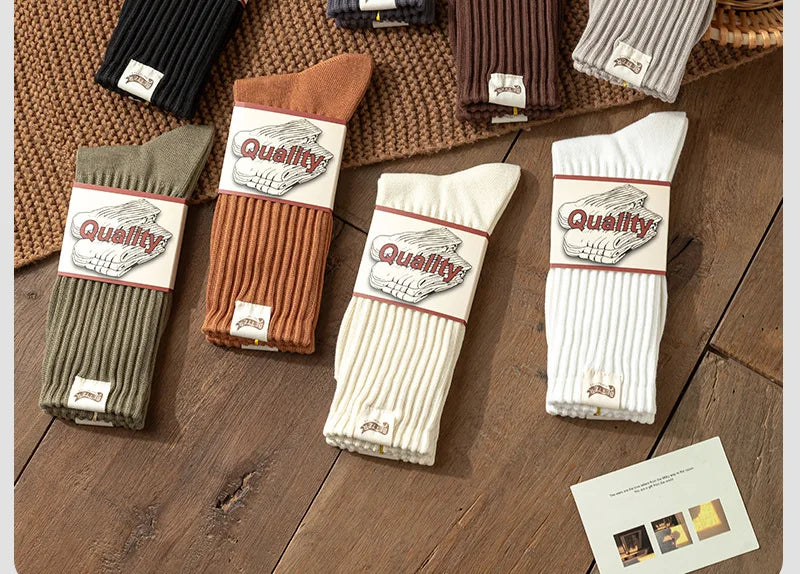 A collection of thick cotton tube socks in various earthy tones including brown, beige, olive green, and white.