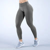 Una modelo vistiendo leggings deportivos grises sin costuras de talle alto y zapatillas blancas.