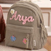 Hellgrüne Cordhosen-Rucksack mit dem Namen Arya in rosa Fadenstickerei.