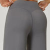 A close-up of a pair of gray high waisted wide leg yoga pants being held by hands.