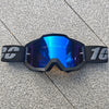 Une paire de lunettes de moto tout-terrain noires avec des verres réfléchissants bleu vif posées sur une surface grise.