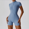 A woman wearing a light blue seamless yoga jumpsuit with a zip collar and short sleeves.