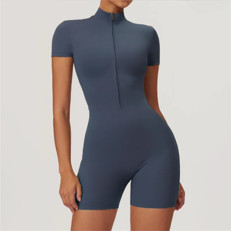 A woman wearing a dark blue seamless yoga jumpsuit with a high collar and zipper.