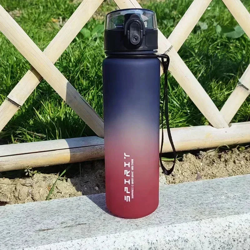 A dark purple and orange sports water bottle is displayed outdoors against a wooden fence.