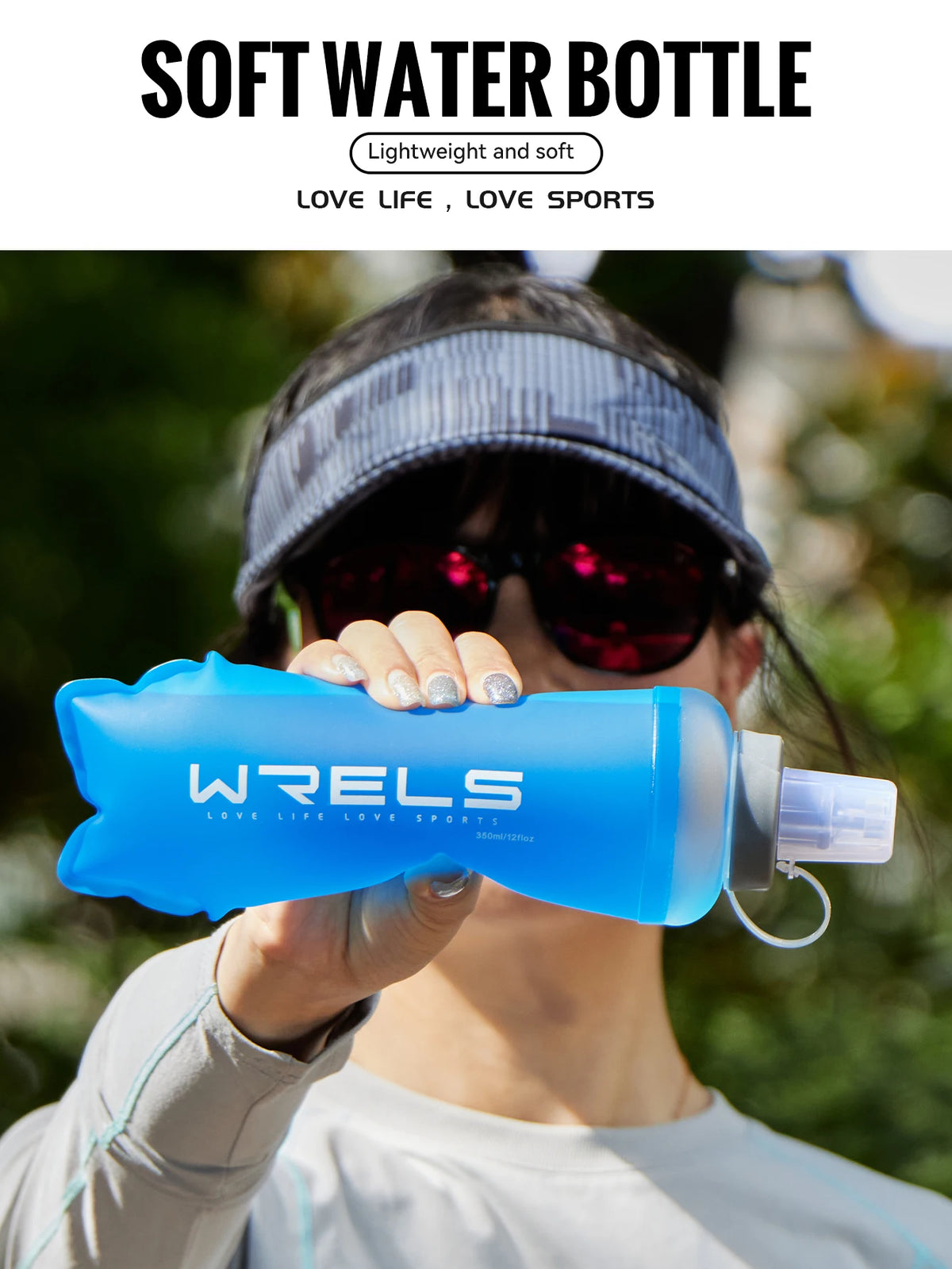 A person holds a bright blue WRELS soft water bottle outdoors while wearing a dark cap and sunglasses.