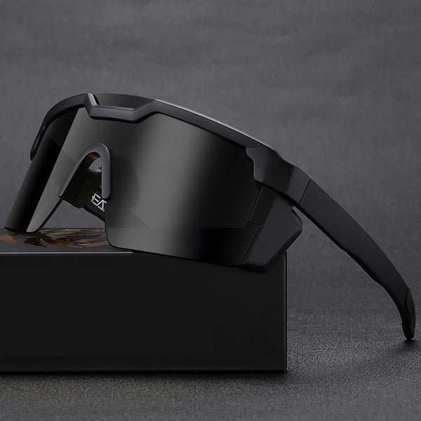 Lunettes de vélo tendance noires de style goggle posées sur une surface sombre.