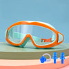 Orange and light blue swimming goggles resting on a green surface.