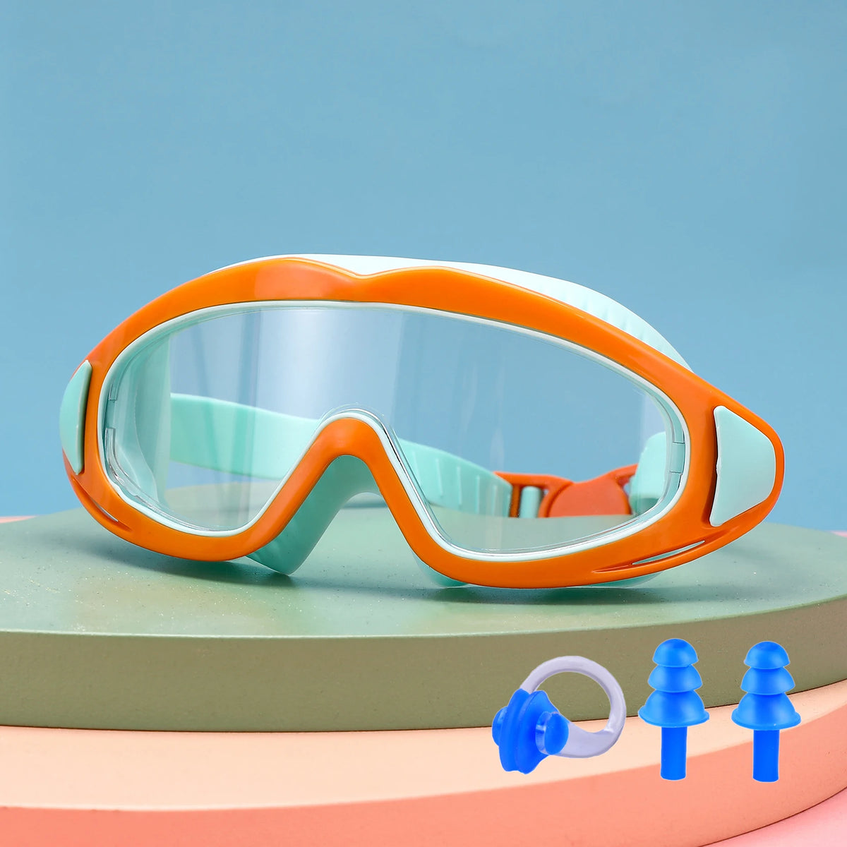 Orange and light blue swimming goggles resting on a green surface.