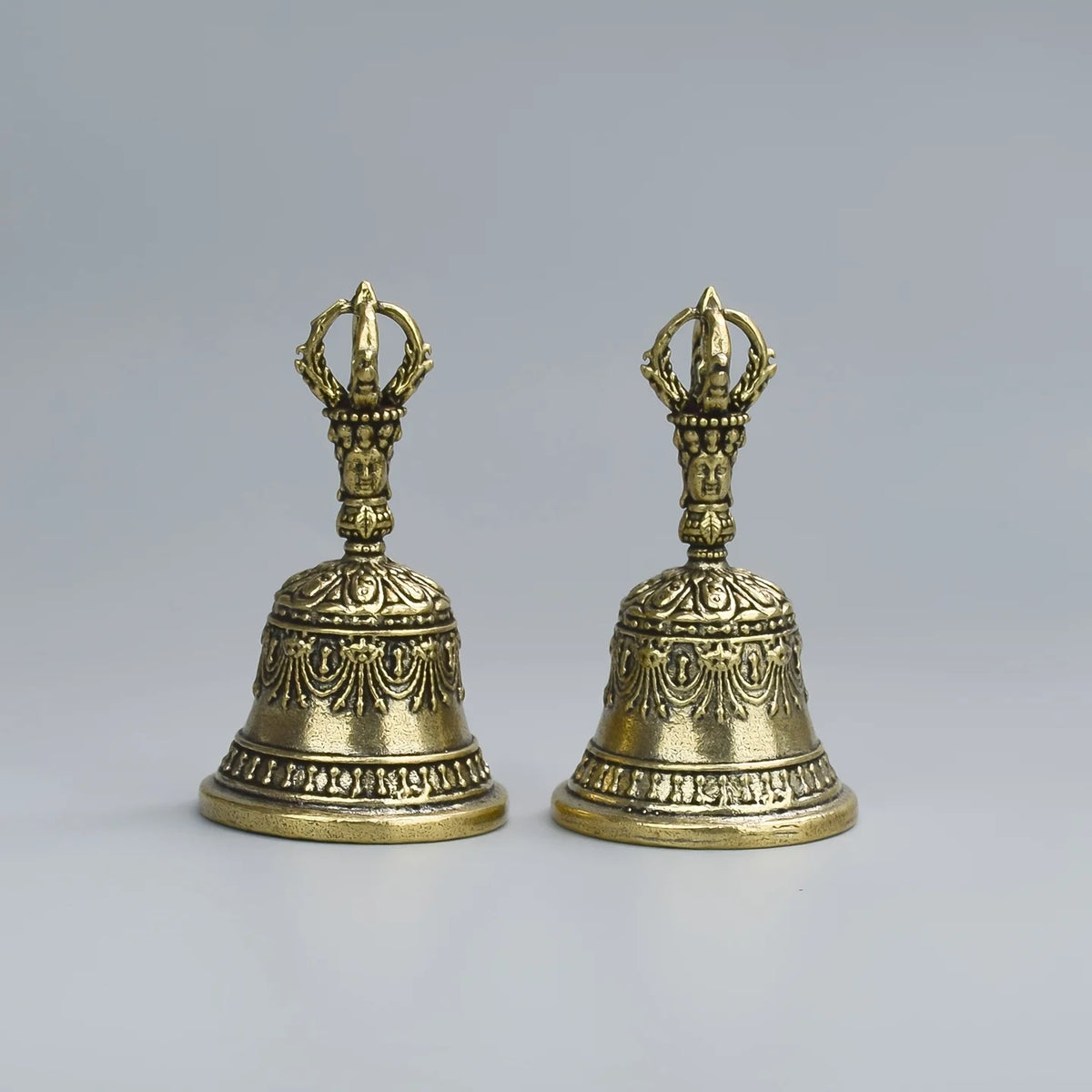 Une paire de cloches ou de maracas en bronze ouvragées avec des têtes décoratives et des gravures.