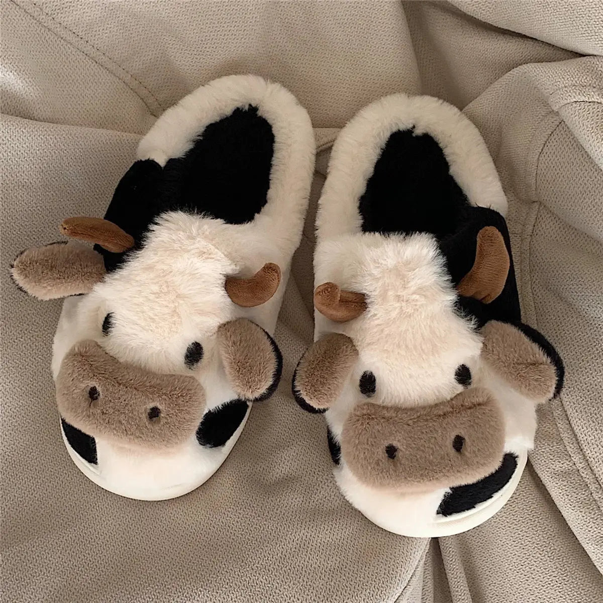 Pair of cartoon cow winter home slippers with black and white fur accents