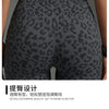 Gros plan d'une femme portant des shorts de yoga taille haute à imprimé léopard gris foncé.