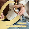 A hand holds a beige thermo mug with a digital temperature display inside a yellow leather travel bag.