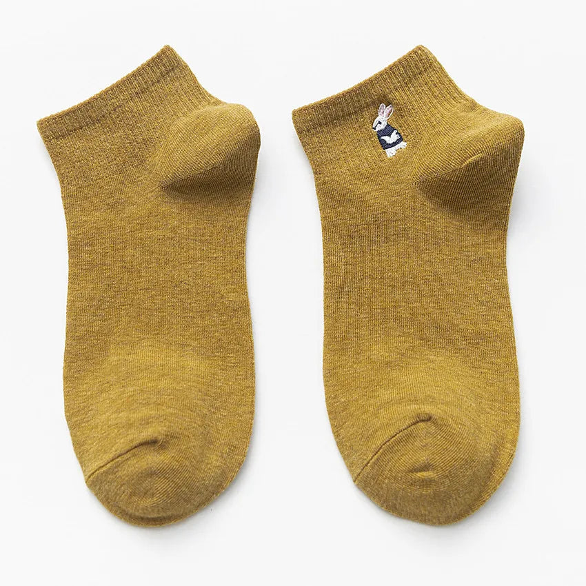 A pair of mustard yellow cotton socks with a small white embroidered design