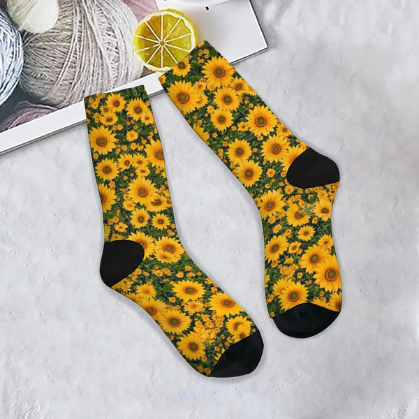 Une paire de chaussettes de coupe respirantes à motif tournesol jaune et vert posées sur une surface blanche à côté d'une tra