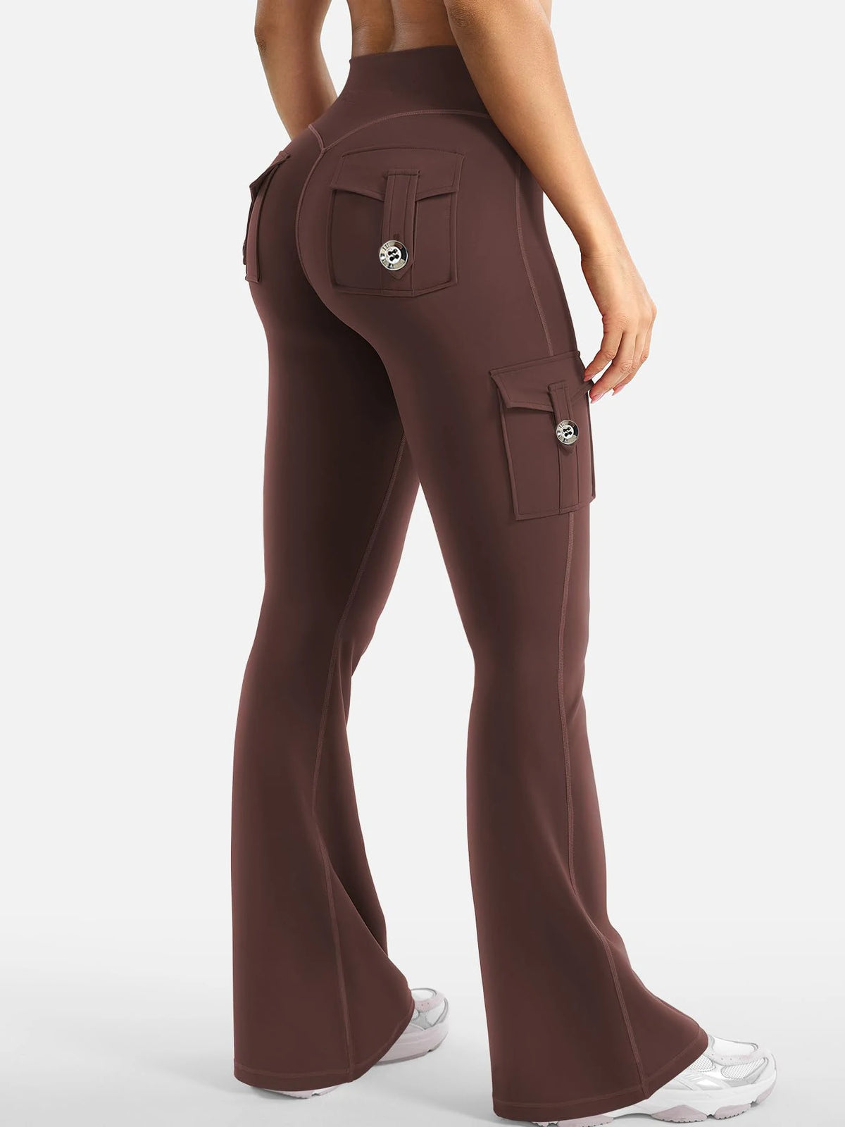 A model is wearing high-waisted, flared fitness pants in a dark brown color.