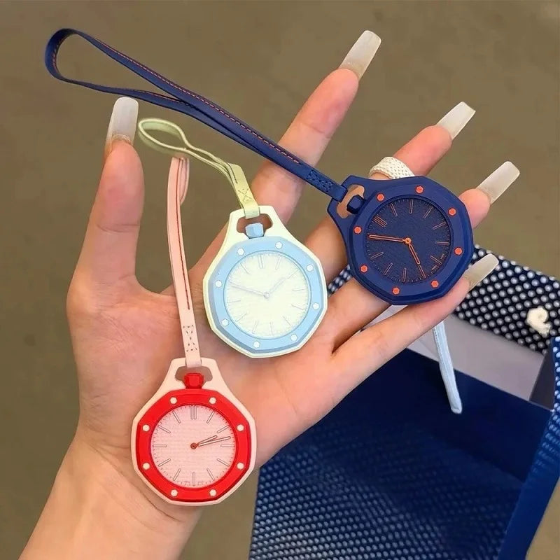 A hand holds an octagonal quartz pocket watch with a blue face and orange bezel, alongside a pink one.