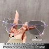 A hand holds a pair of purple photochromic eyeglasses with diamond accents against a light gray background.
