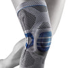A close-up of a gray knee brace with blue accents, worn on a person's leg.