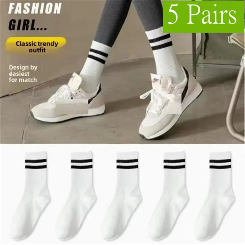 Five pairs of white socks with black stripes shown on legs and individual view.