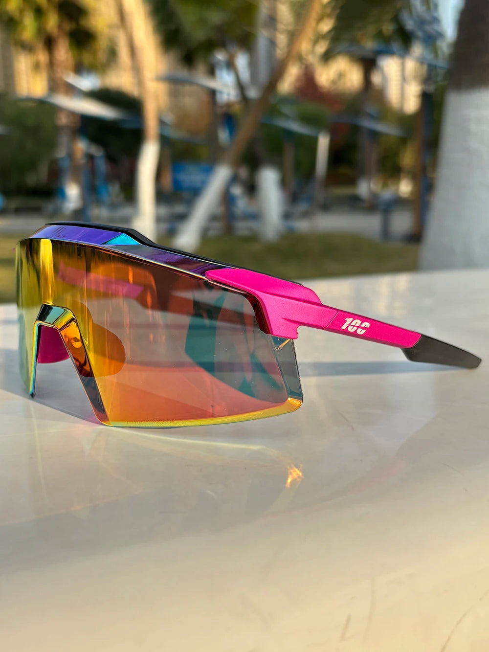 A pair of vibrant, multi-colored sports sunglasses resting on a white surface.