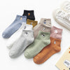 A collection of embroidered cotton socks in various colors and patterns laid out on a white surface.
