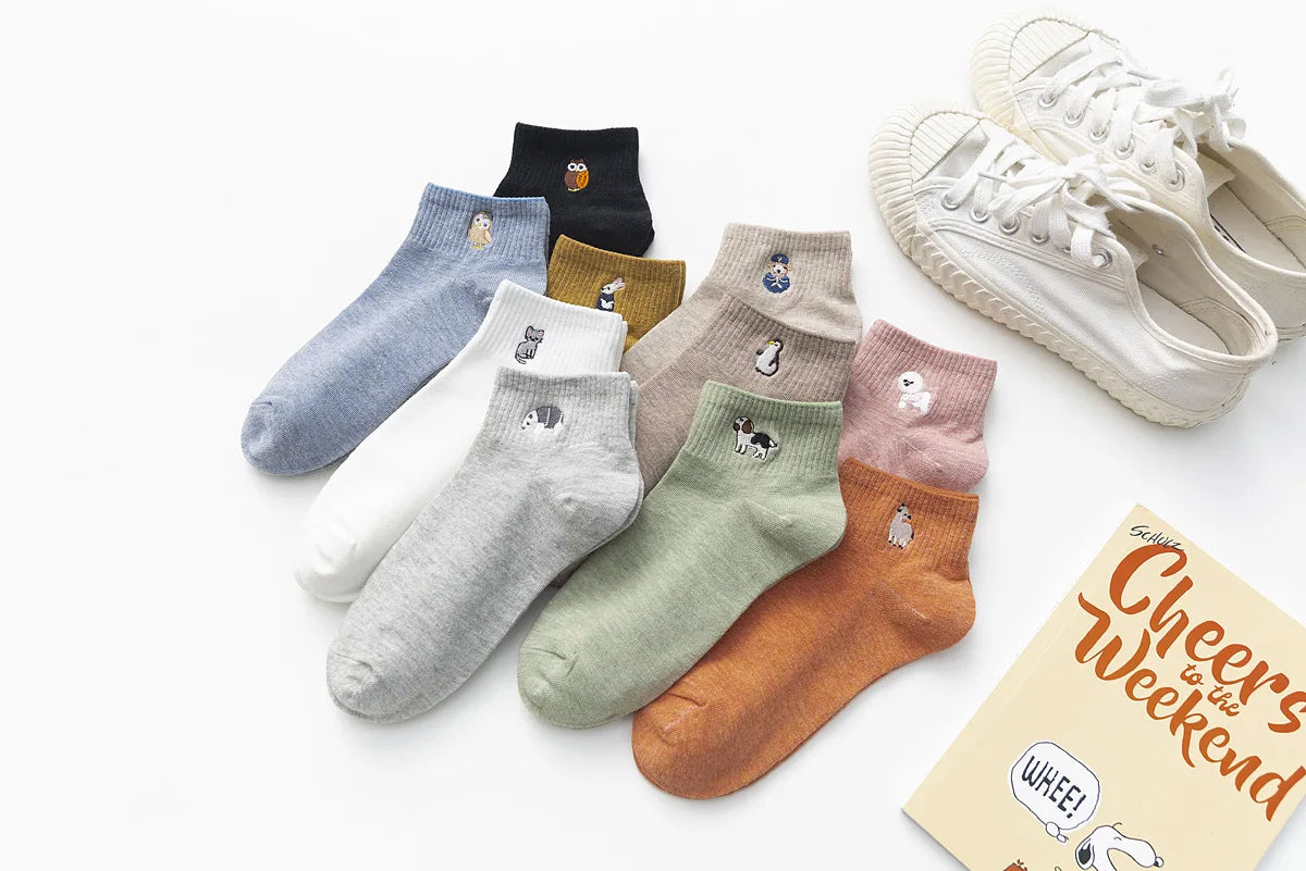 A collection of embroidered cotton socks in various colors and patterns laid out on a white surface.