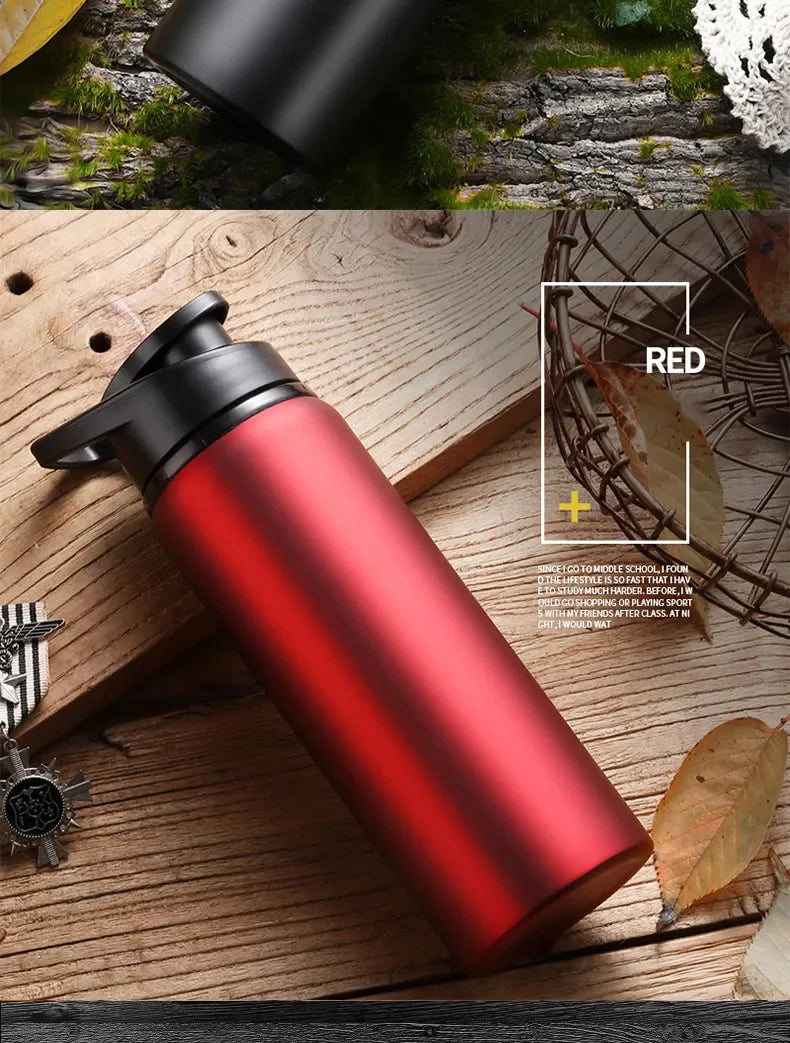 A red and black leakproof aluminum portable water bottle resting on a wooden surface with natural elements.