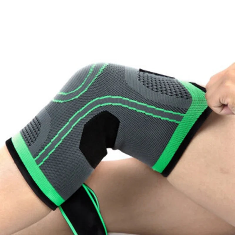 A close-up of a black and gray adjustable sports knee pad worn on a person's leg.