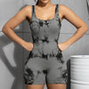 A model wearing a gray tie-dye sport jumpsuit, posing against a gray wall.