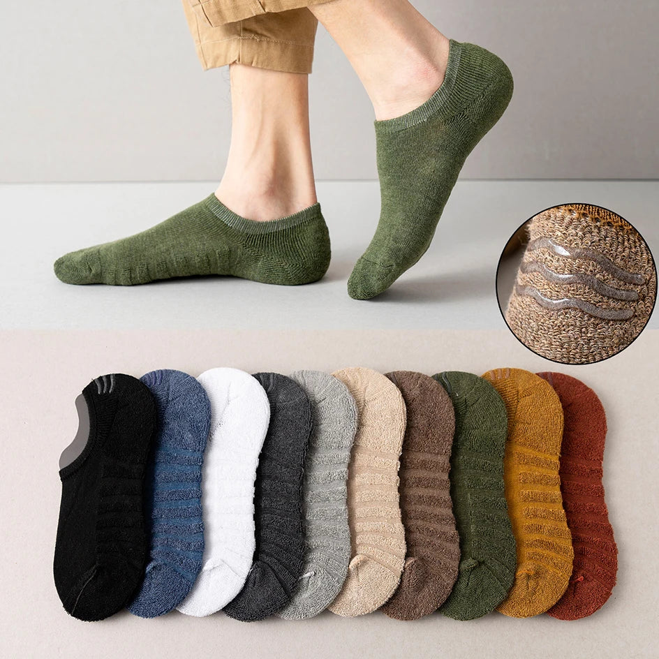 A pair of olive green men's cotton crew socks worn on a foot, with a row of various colored socks displayed below.