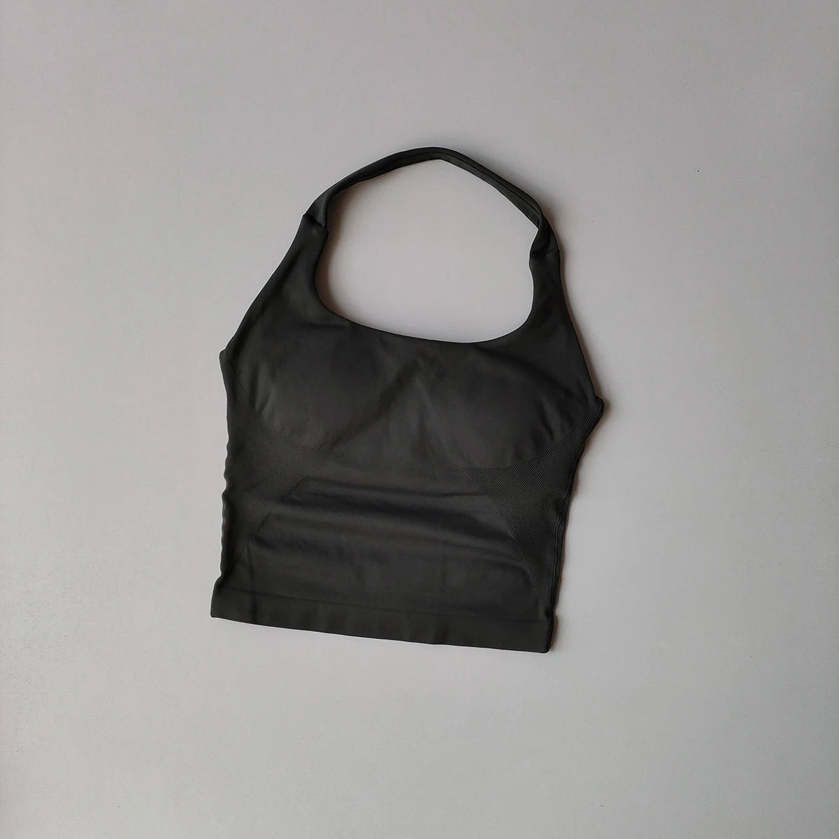 Haut sans couture noir à col, pour yoga et fitness, présenté sur fond gris clair.