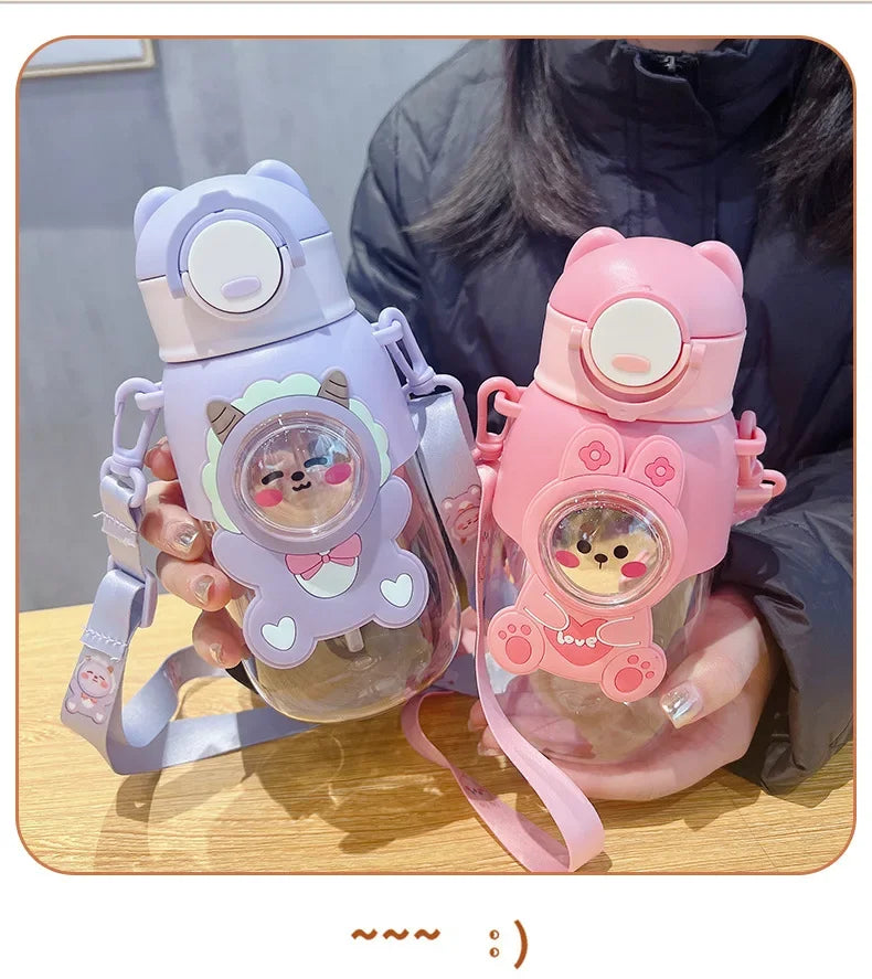 A person holds a pink and purple leak-proof water bottle shaped like a cartoon animal.