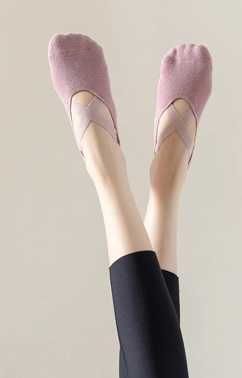 Pair of pink non-slip yoga and gym socks with silicone grip worn on a person's feet.