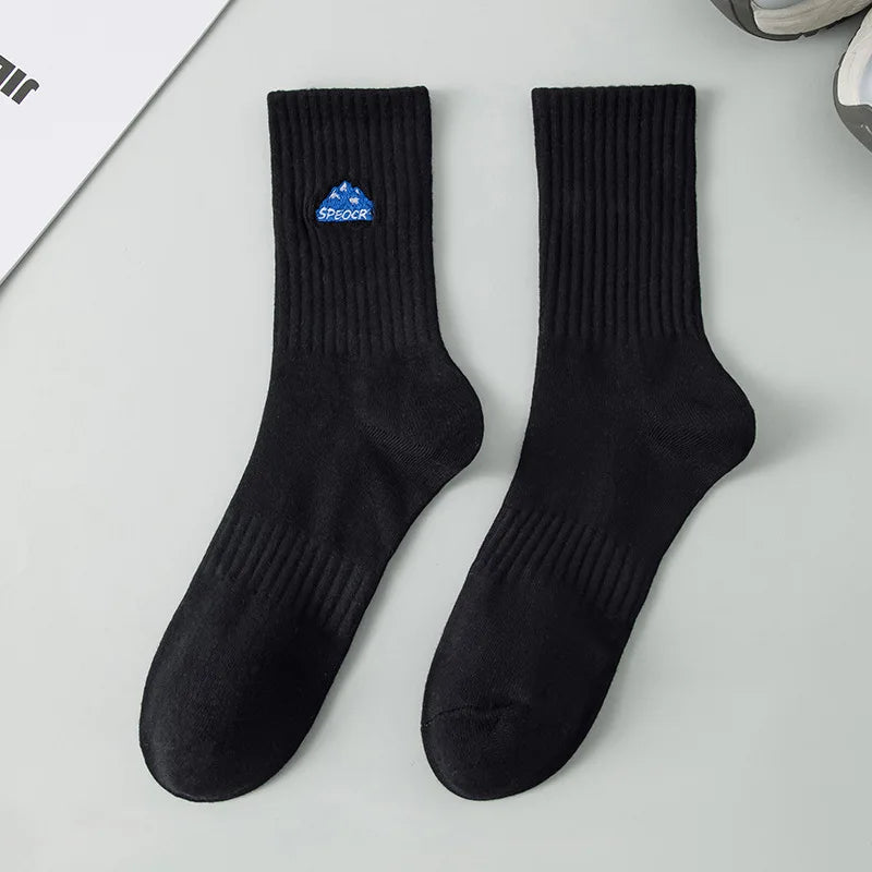 A pair of black men's athletic crew socks with a blue embroidered logo on the heel.