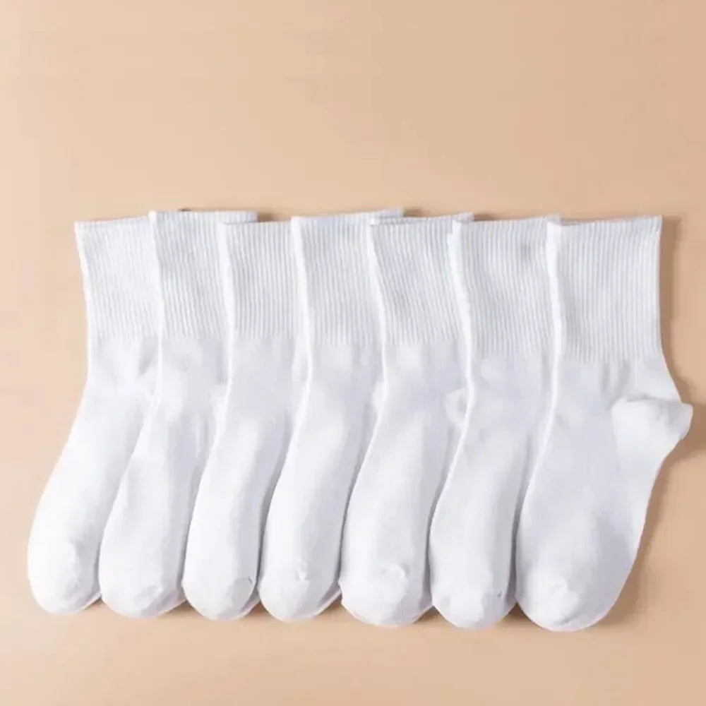 Une rangée de chaussettes en tricot blanches mi-mollet pour femmes, posées à plat sur un fond beige clair.