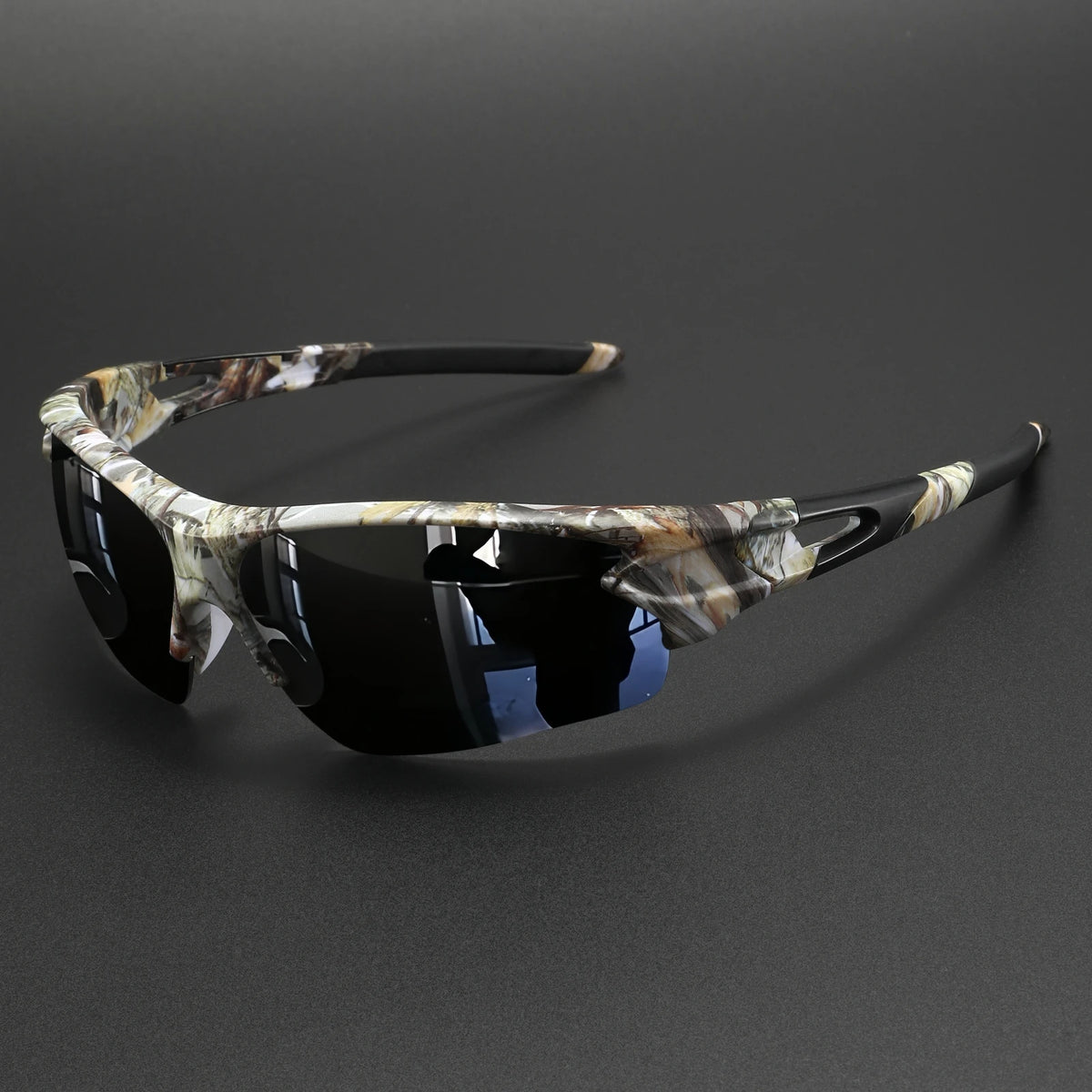 A pair of tortoiseshell patterned wraparound sports sunglasses with dark lenses resting on a dark surface.