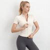 A woman wearing a beige lightweight slim fit sports yoga top and dark gray leggings.