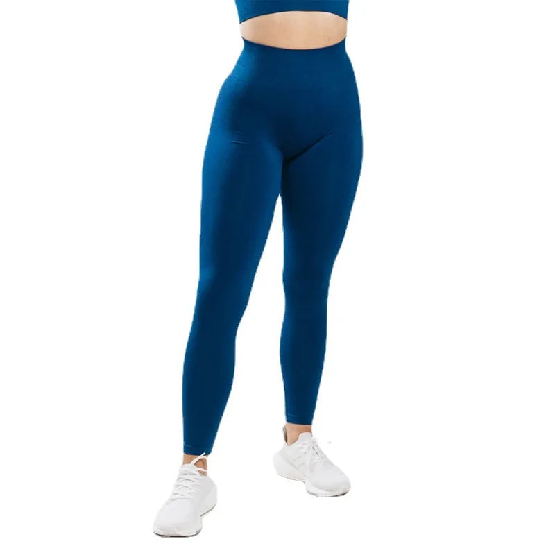 Une personne portant des leggings de yoga sans couture bleu royal taille haute et des baskets blanches.