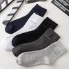 A collection of five men's bamboo fiber socks in various shades of black, gray, and white are displayed on a light surface.