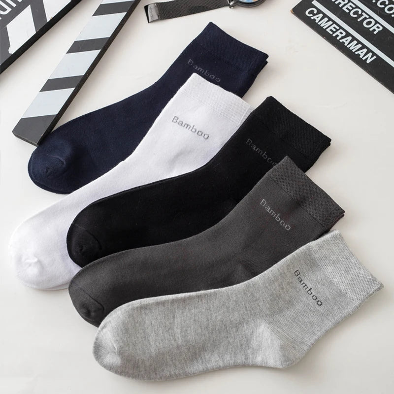 A collection of five men's bamboo fiber socks in various shades of black, gray, and white are displayed on a light surface.