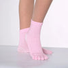 Pink yoga socks with white polka dots worn on a foot