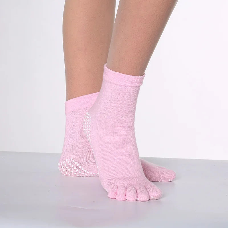 Pink yoga socks with white polka dots worn on a foot