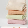 A stack of four light-colored cotton yoga socks in various shades of beige and pink.