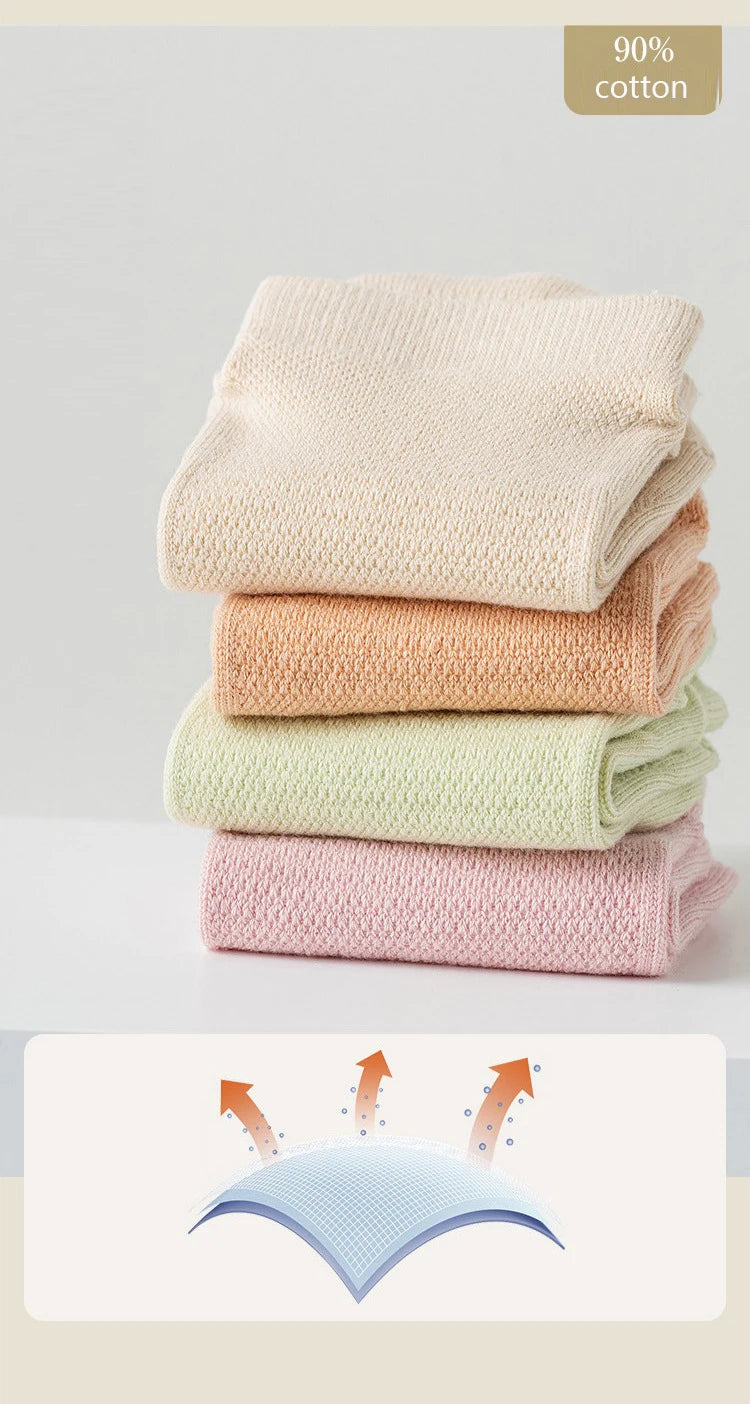 A stack of four light-colored cotton yoga socks in various shades of beige and pink.