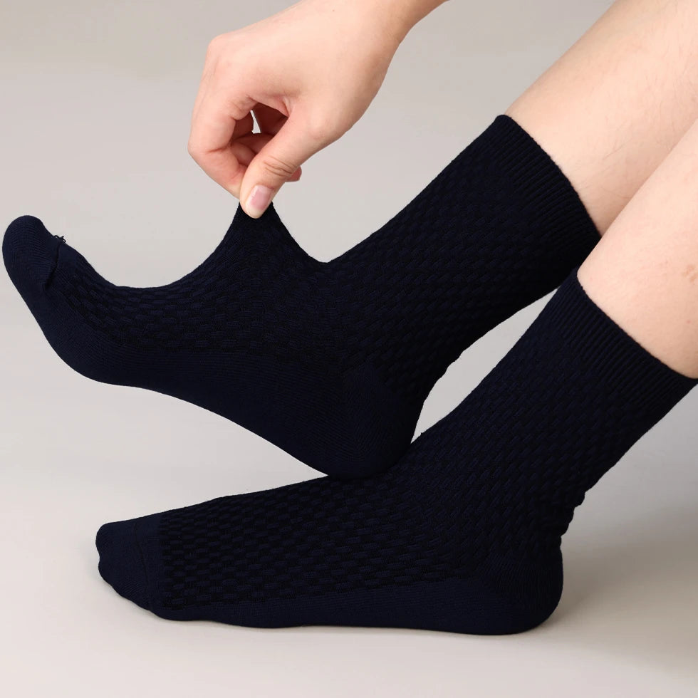 A hand is putting on a pair of navy blue bamboo fibre anti-odor socks.
