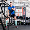 A muscular man wearing compression socks is exercising in a gym setting with various fitness equipment visible.