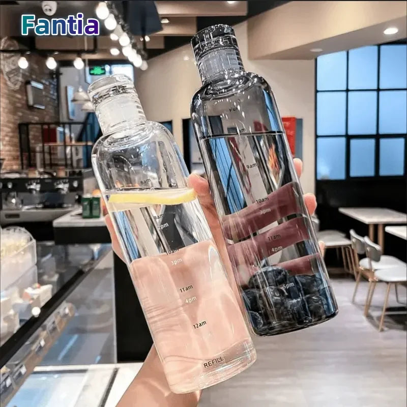 A clear insulated water bottle with a time scale is held up against a blurred background.