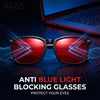 Pair of red anti blue light blocking glasses resting on a dark surface with glowing circuit board patterns.